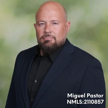 Portrait of a bald man with a beard in a dark suit.