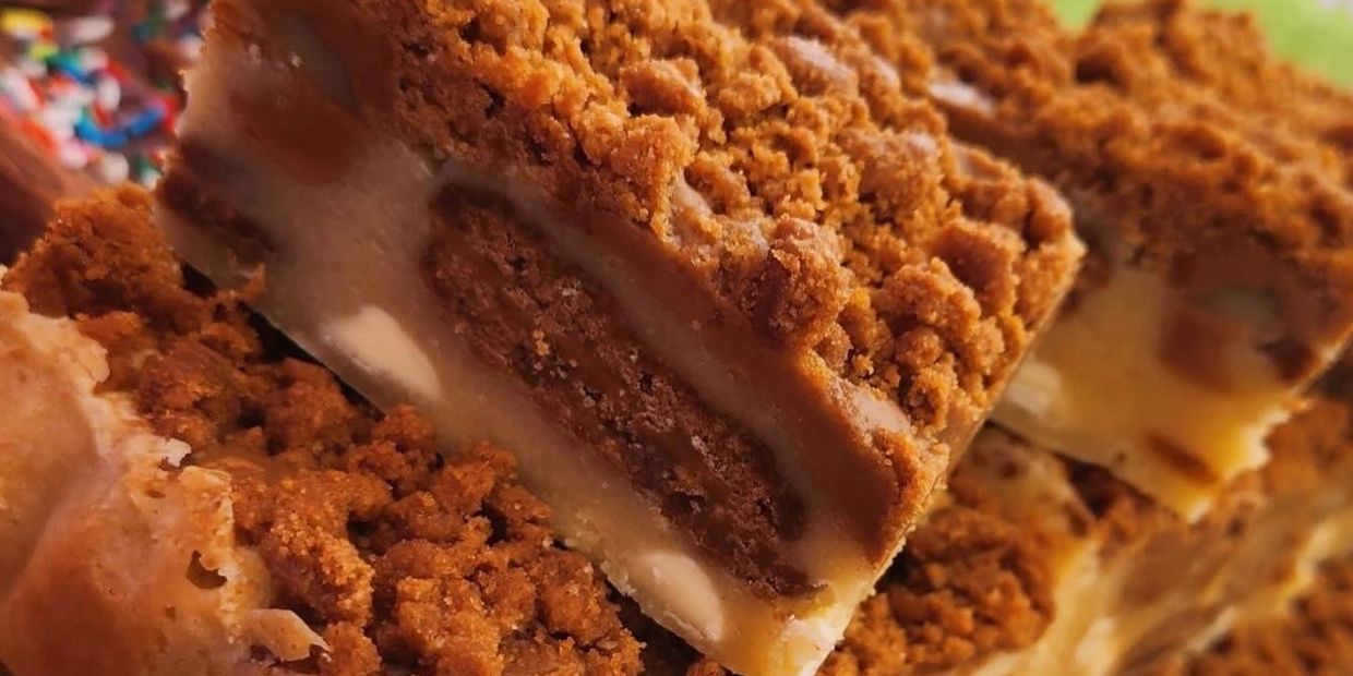 Close-up of crumbly layered dessert bars with a creamy filling.