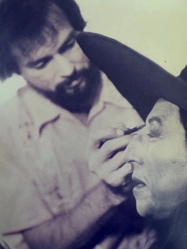 Joe Blasco applies makeup to another person wearing theatrical costume and hat the witch in the Original Wizard of Oz.