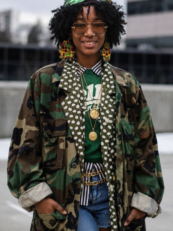 Person wearing eclectic layered clothing with camouflage and polka dots.