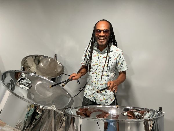 Smiling man playing steel drums.