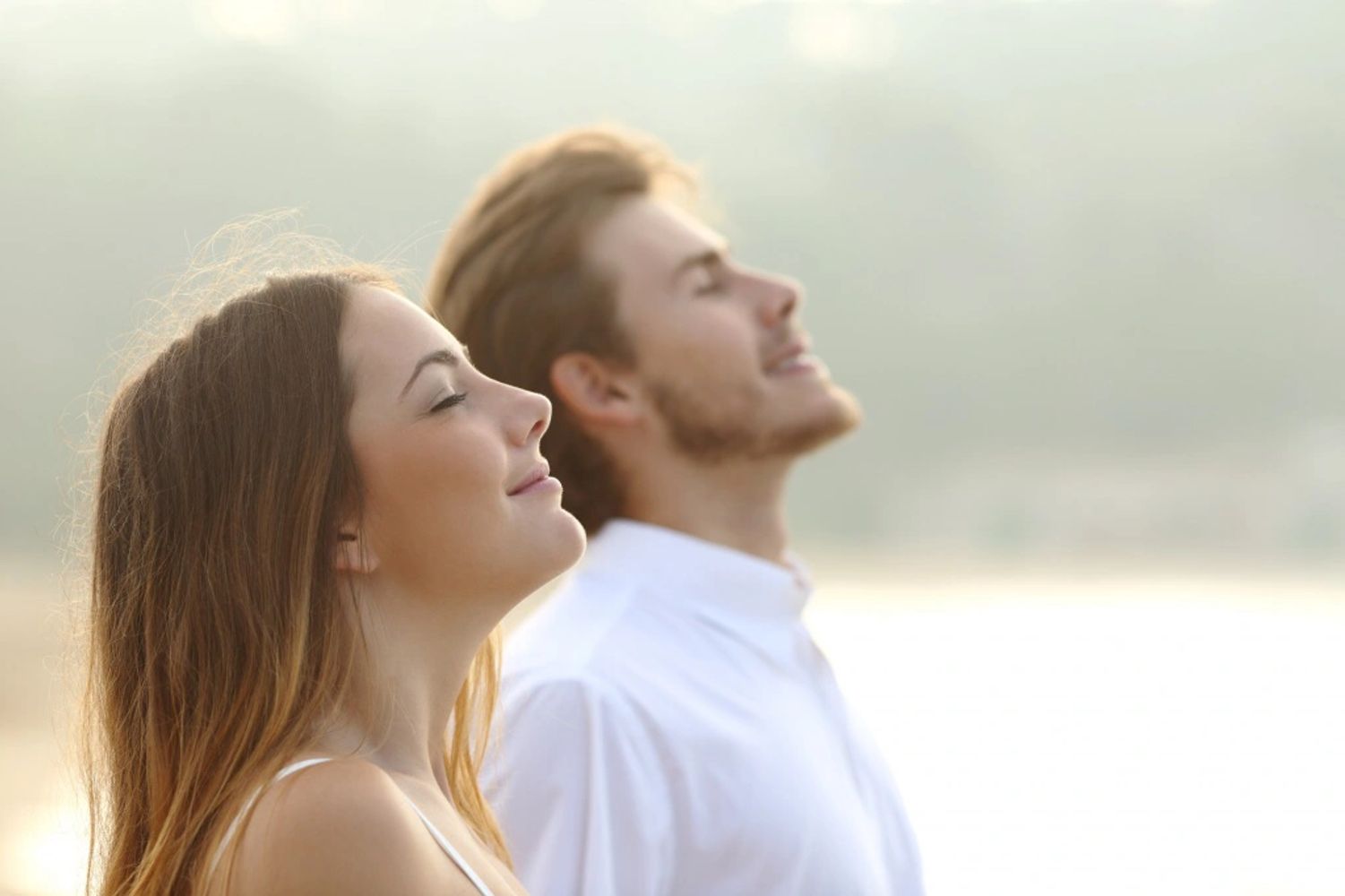 A young couple enjoying a peaceful moment with closed eyes and smiles.