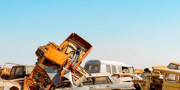 A pile of old, rusty cars against a clear blue sky.