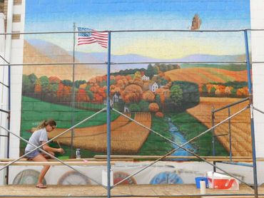Nikki Frank putting finish on the outdoor Mount Carmel VFW mural, America the Beautiful