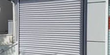 Closed white metal rolling shutter on a modern building.