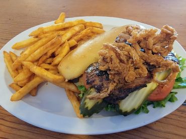 Grilled sandwich with fried soft shell crab and fries on a white plate.
