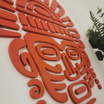 Close-up of an orange Aztec-style wall art with intricate designs.