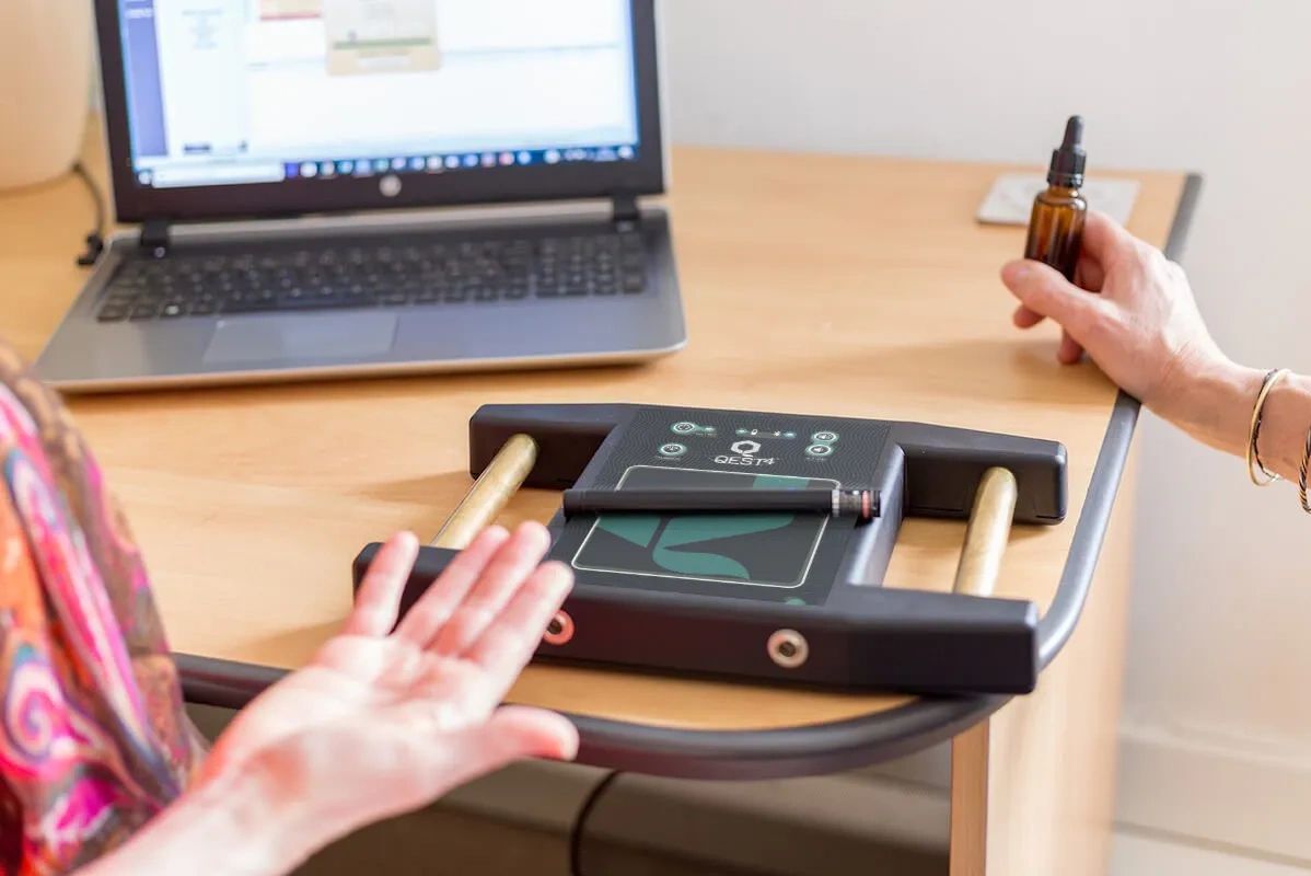 QEST device used with a laptop and a brown dropper bottle.