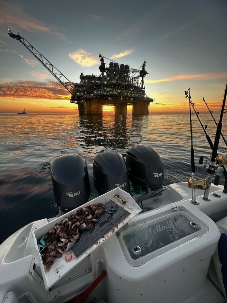 Deep sea fishing at sunset near oil rig