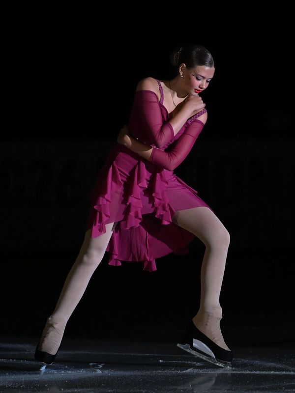 Figure skater in elegant purple dress performing on ice.