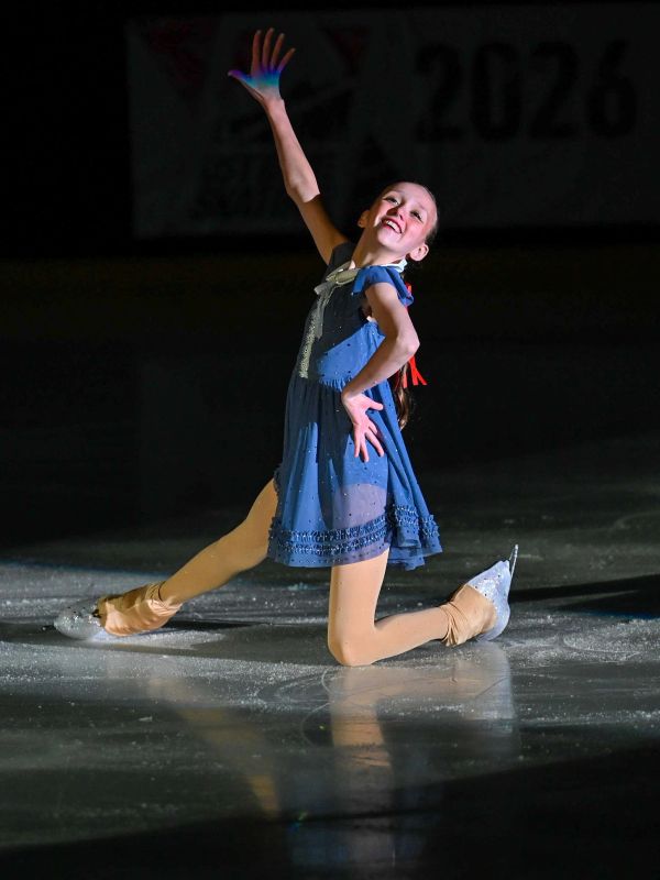 Young girl figure skating with a pose on the ice.