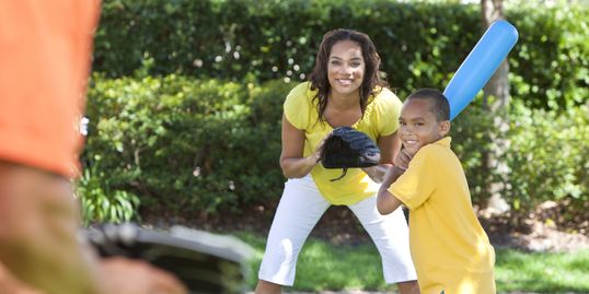 Young boy and his mom playing baseball outdoors