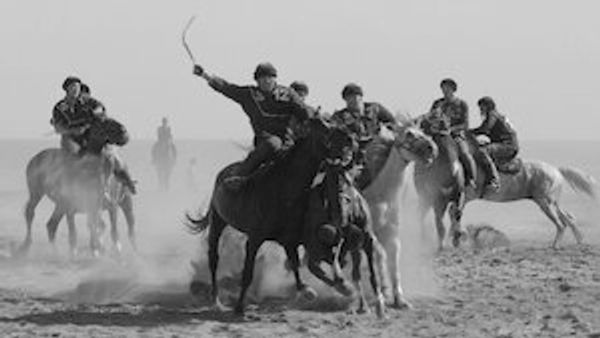 Group of men playing horseback polo on a dusty field.