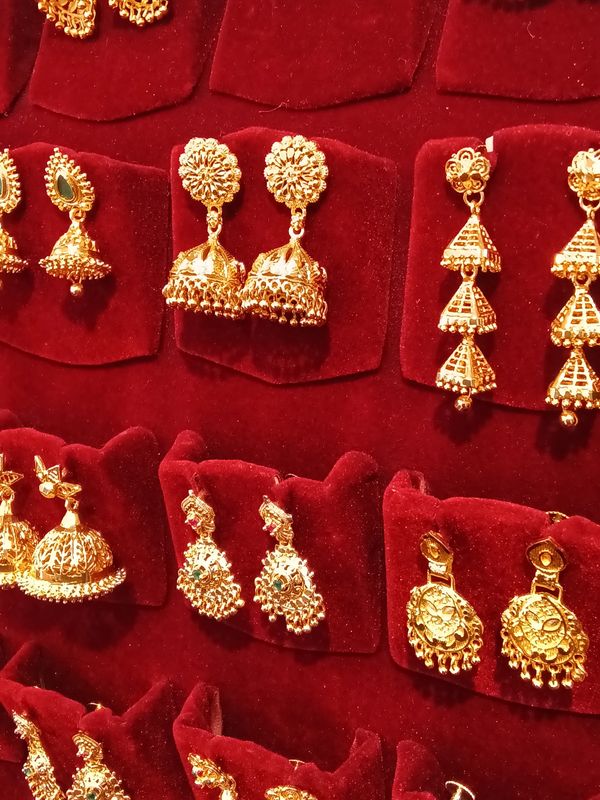 Intricate gold earrings displayed on red velvet stands.