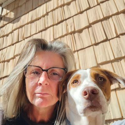 Woman with glasses and dog pose together.