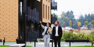 Two professionals walking and discussing outside a modern building.