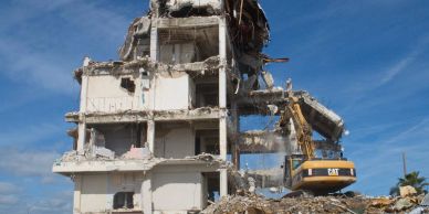 A building under demolition with heavy machinery at work.