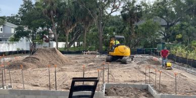 Construction site with excavator and worker preparing foundation.