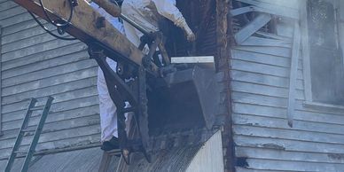 Firefighter using equipment to access a damaged building amid smoke.