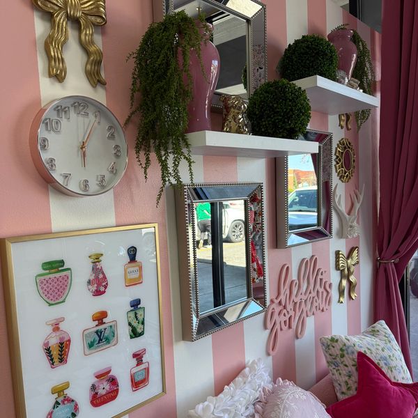 Decorative pink and white striped wall with mirrors, clock, and plants.