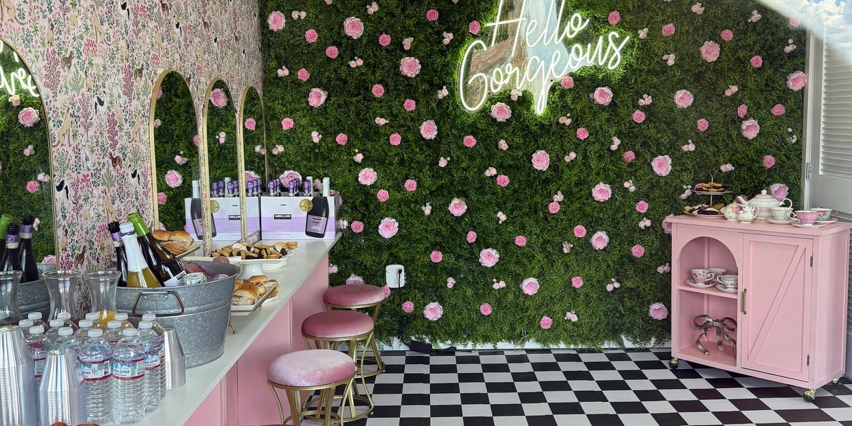 Chic pink and floral-themed room with refreshments and a neon sign.