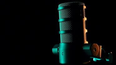 Close-up of a vintage microphone with dramatic lighting on a dark background.