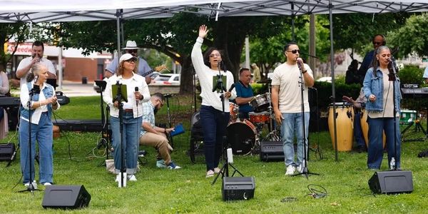 Band performing outdoors under tents at a park.