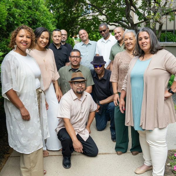 A group of diverse adults posing outdoors and smiling.