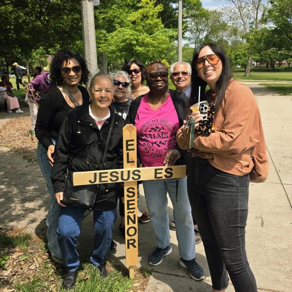 Group holding a wooden cross that says 'JESUS ES EL SEÑOR'.