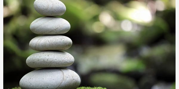 Stack of smooth stones balanced on mossy ground in nature.