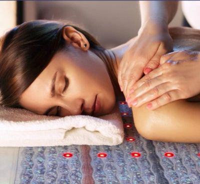 Woman receiving a relaxing massage on a therapeutic mat with red light therapy.