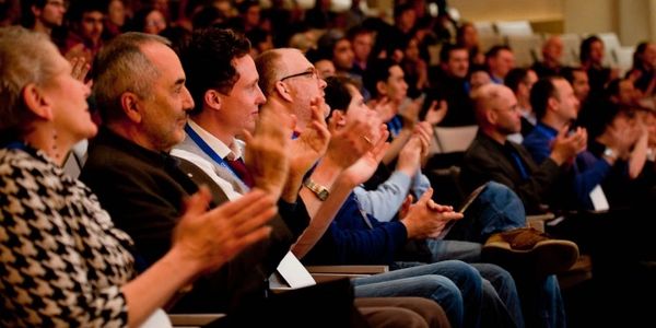 Audience members applauding at a seminar.