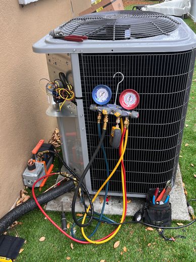 Air conditioning unit being serviced with gauges and tools attached.