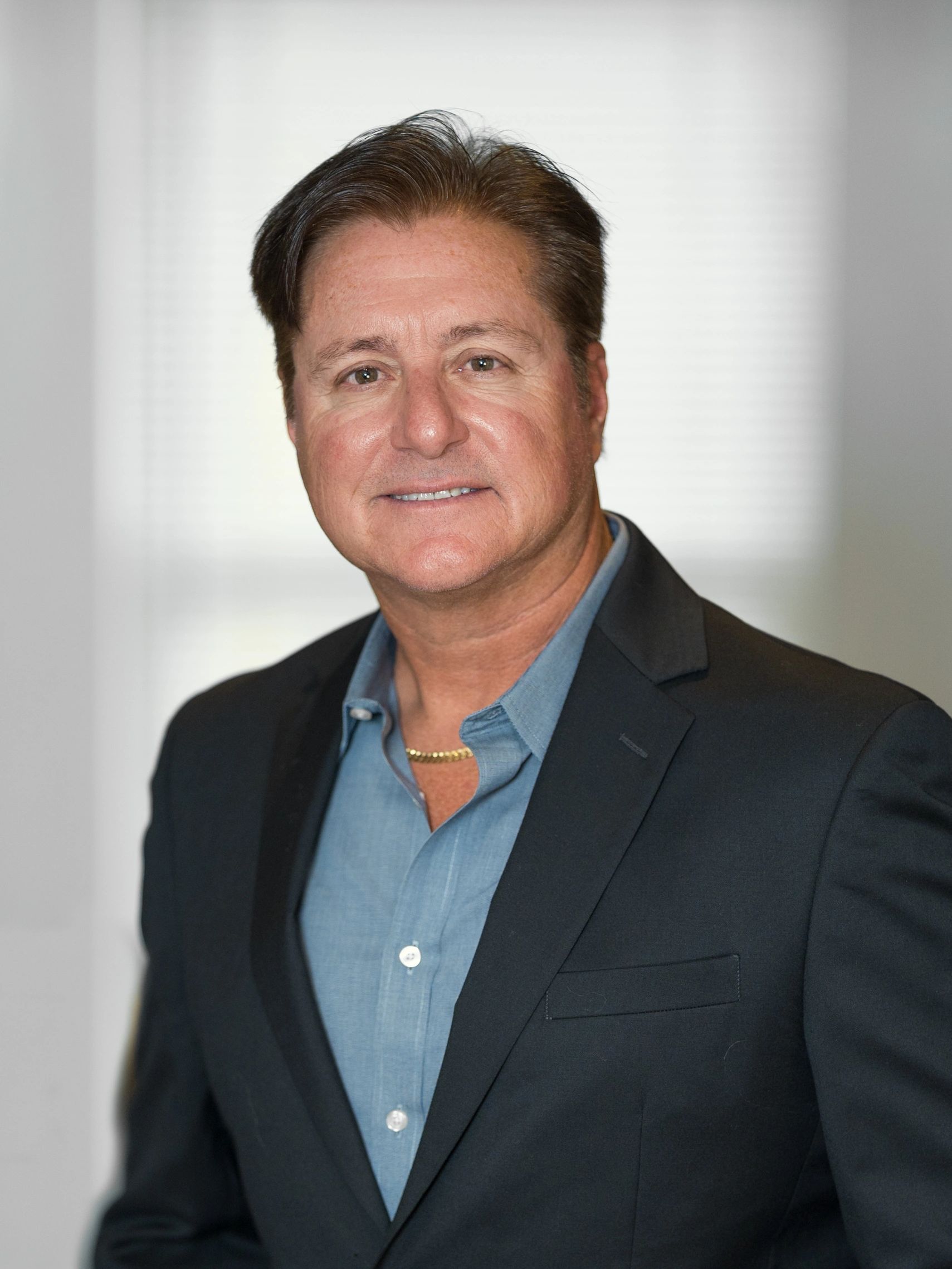 A headshot of David Cappielo wearing a suit jacket with an open collar.