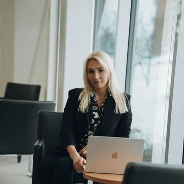 Businesswoman sitting with a laptop by the window in a modern office.