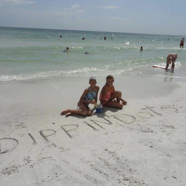two children, on a beach,in Florida USA, writing the word Dippin Dots in the sand.