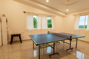 A bright room with a ping pong table and foosball game.