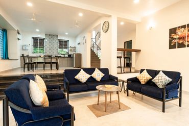 Modern living room with blue sofas and open kitchen in the background.