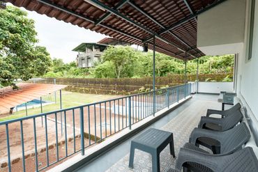 Covered veranda with plastic chairs and lush garden view.