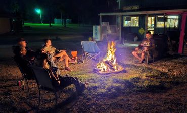 people sitting around a campfire at night.