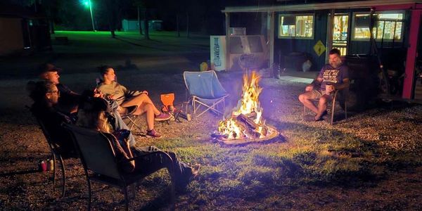 Family gathered around a campfire at night.