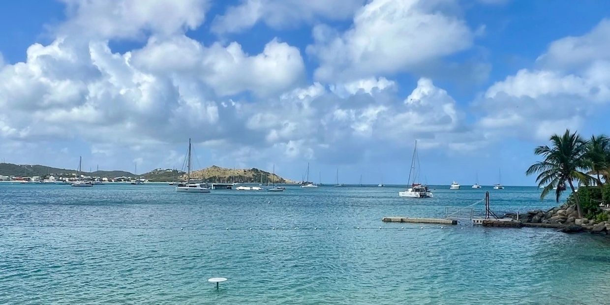 Calm sea with boats under a partly cloudy sky.