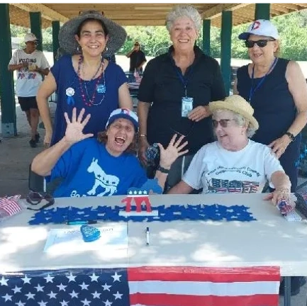 Group of cheerful adults at a patriotic event under a pavilion.
