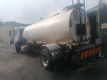 White tanker truck parked near a building on an overcast day.