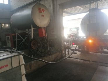 Fuel transfer hose connects tanker to storage tank inside a garage.