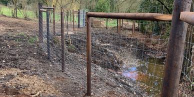 Fence in a Muddy Field with Ditch Filled with Water