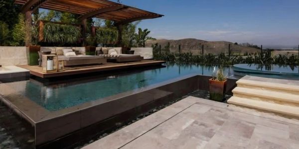 Modern outdoor pool area with seating and mountain view.