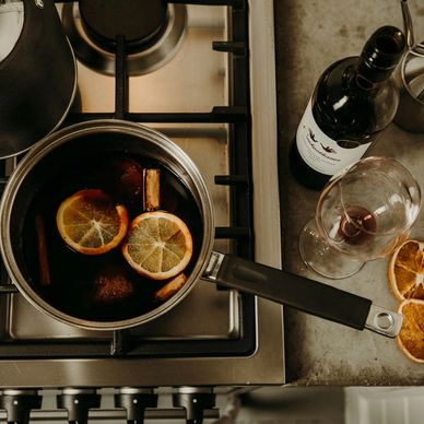 Mulled wine on a stove top, wine glasses and oil bottle