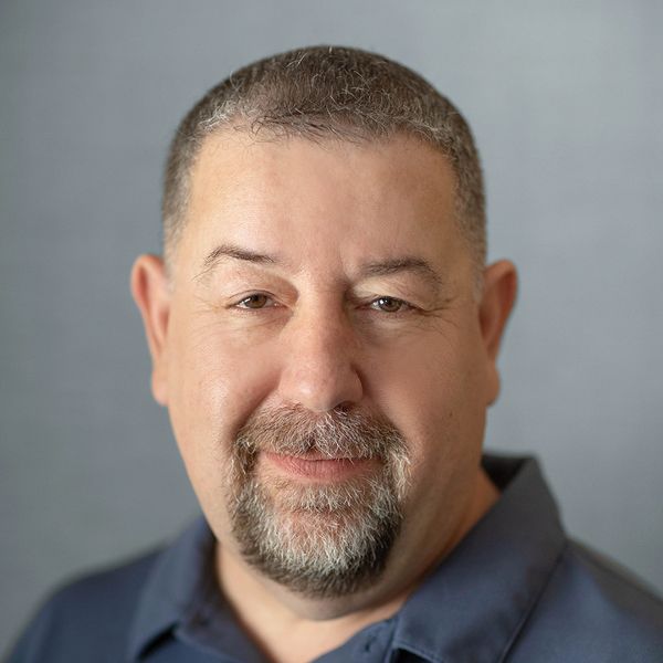 Portrait of a middle-aged man with short hair and a goatee, smiling gently.