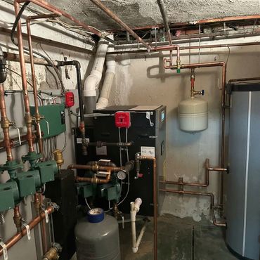 Complex basement heating system with pipes and tanks.